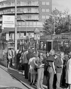 855038 Afbeelding van wachtende mensen bij een bushalte met abri voor de stadsbussen aan de noordzijde van het ...